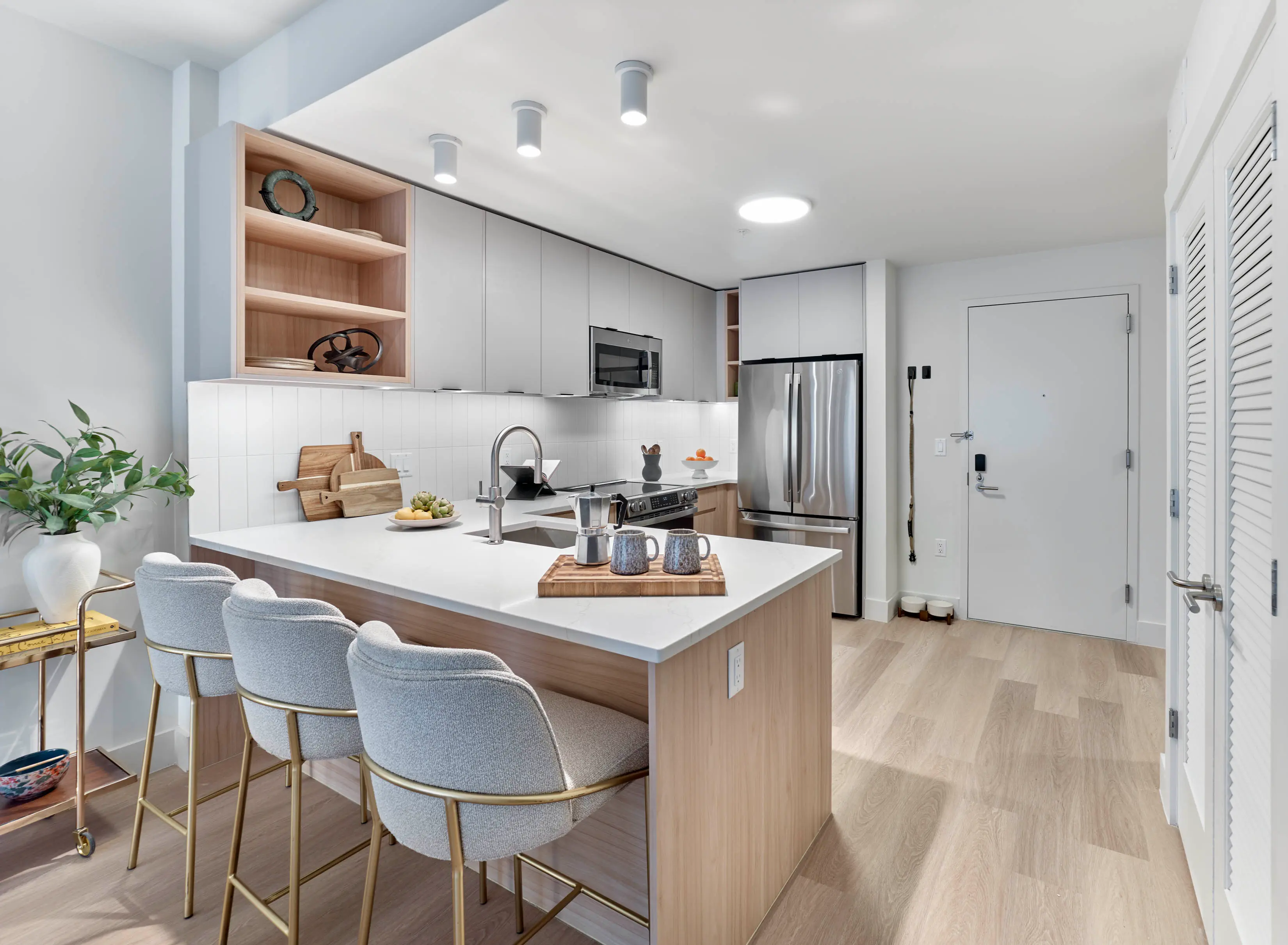 Modern apartment kitchen featuring white countertop island, and light wood cabinetry